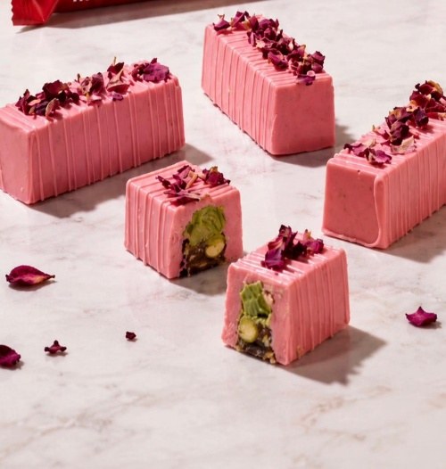 Pink rose chocolate with dried petals, one piece cut open to show the pistachio centre